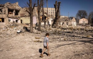 A child walks in front of a damaged school in the city of Zhytomyr, in northern Ukraine (March 23, 2022)